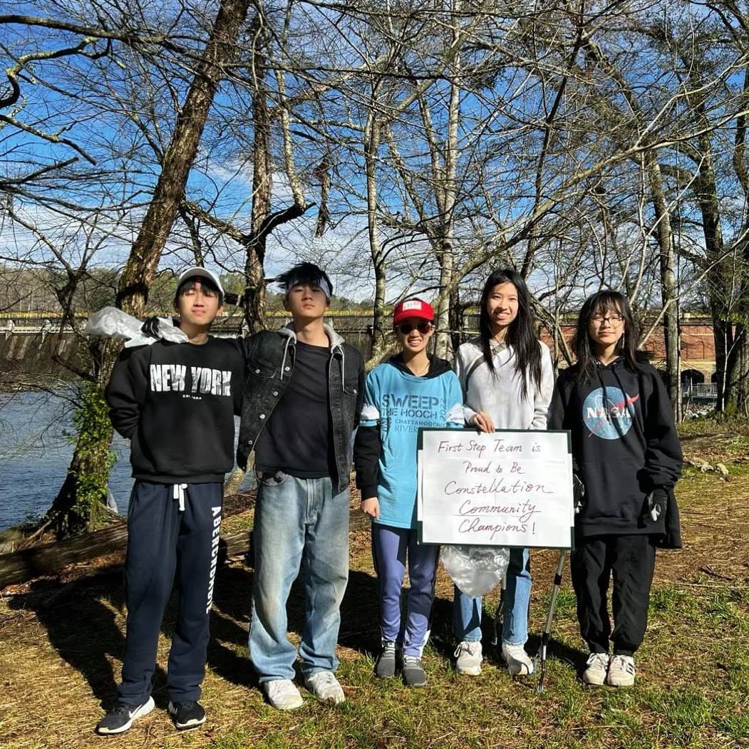 First Step volunteers holding a community support check after a river cleanup