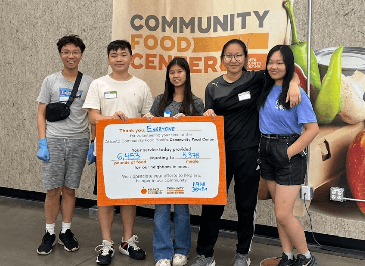 Four volunteers holding a community food bank recognition check