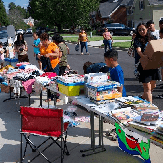 Volunteers running a community garage sale with tables of donated items