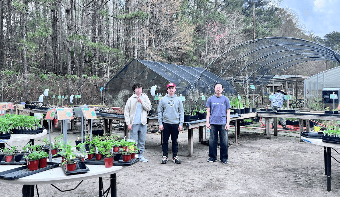First Step volunteers helping with plants inside a community greenhouse