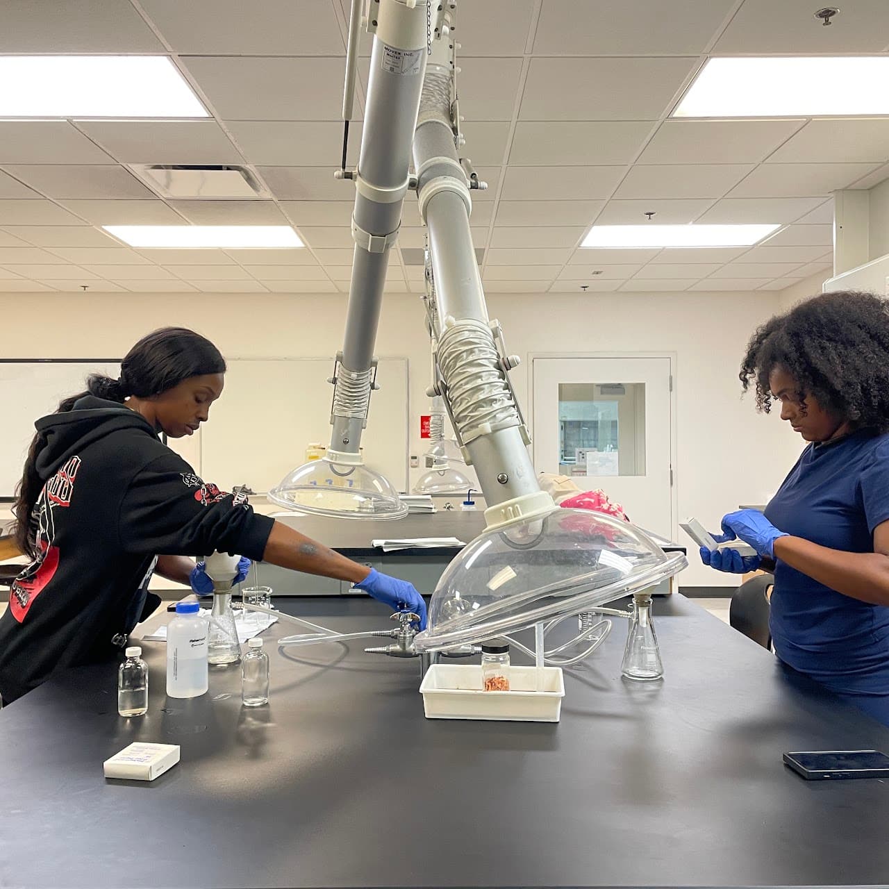 Students processing water samples under laboratory extraction equipment