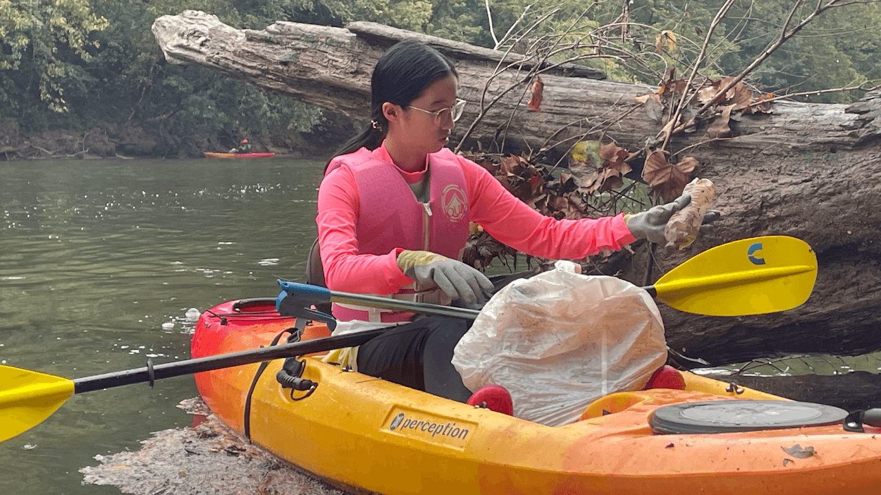 First Step volunteer collecting trash from the river by kayak