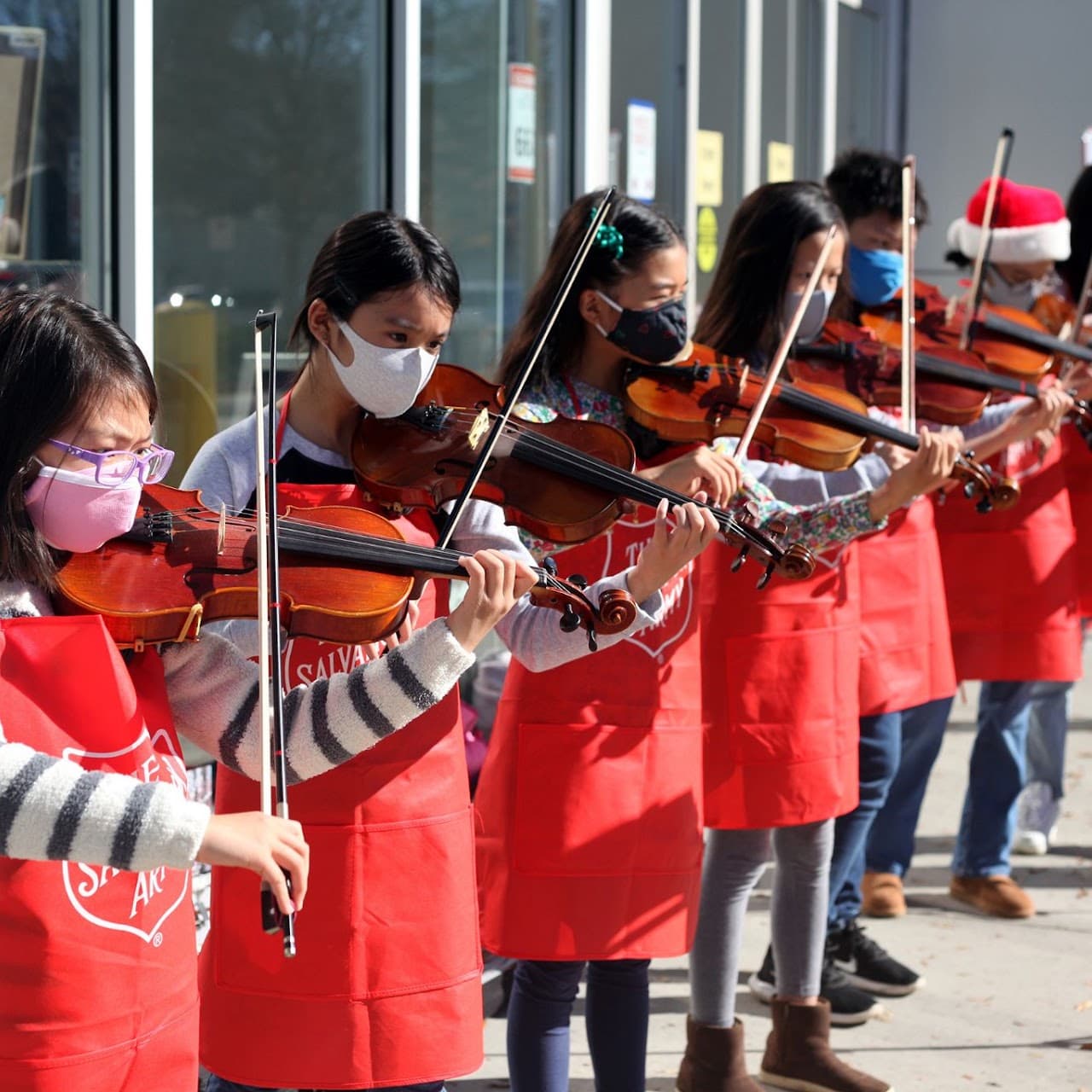 Student violinists performing together in red holiday clothing